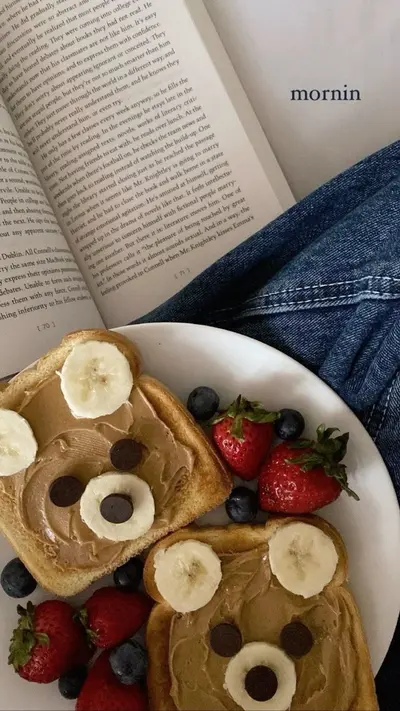Zwei Toastscheiben mit Erdnussbutter, Bananen und Schokodrops als Bärengesichter dekoriert auf einem weißen Teller.