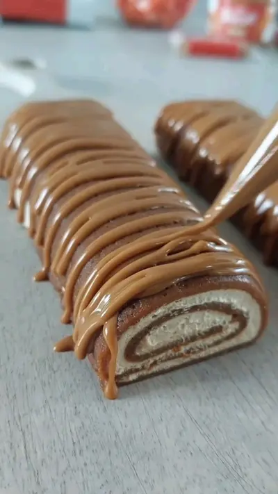 Un gâteau roulé décoré d'un nappage au spéculoos versé avec soin sur le dessus.