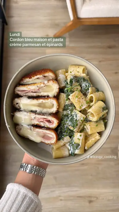Un bol contenant un cordon bleu tranché au fromage fondant et des pâtes rigatoni à la sauce crème, épinards et parmesan.