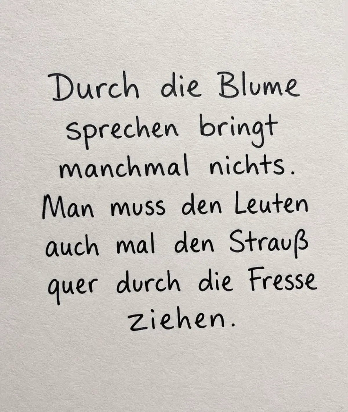 Ein handgeschriebener Spruch auf weißem Papier über die Notwendigkeit von direkter Kommunikation.