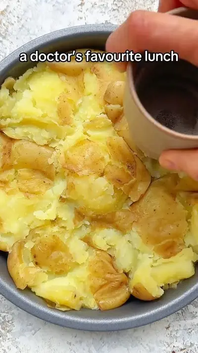 Une main écrase des pommes de terre cuites dans un moule rond avec le fond d'une tasse.